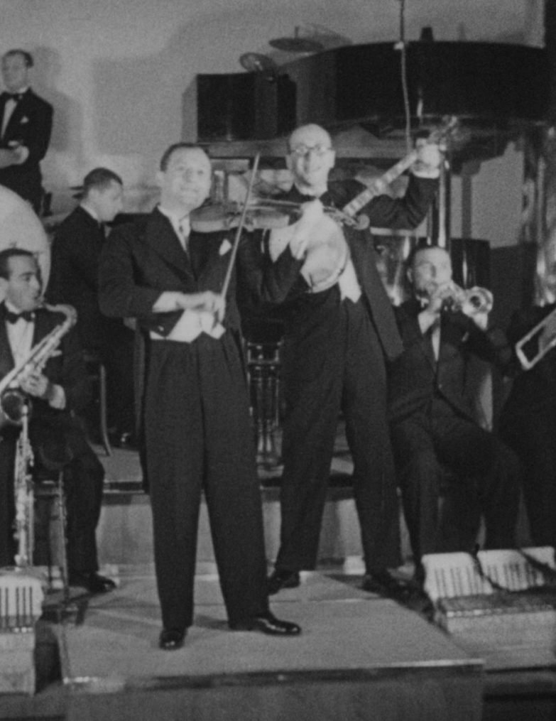 Julian Front i Zygmunt Heyman na estradzie kawiarni Adria przy Moniuszki 10, luty 1932 — kadr z filmu „Dziś mamy bal”. Filmoteka Narodowa — Instytut Audiowizualny, Fototeka.