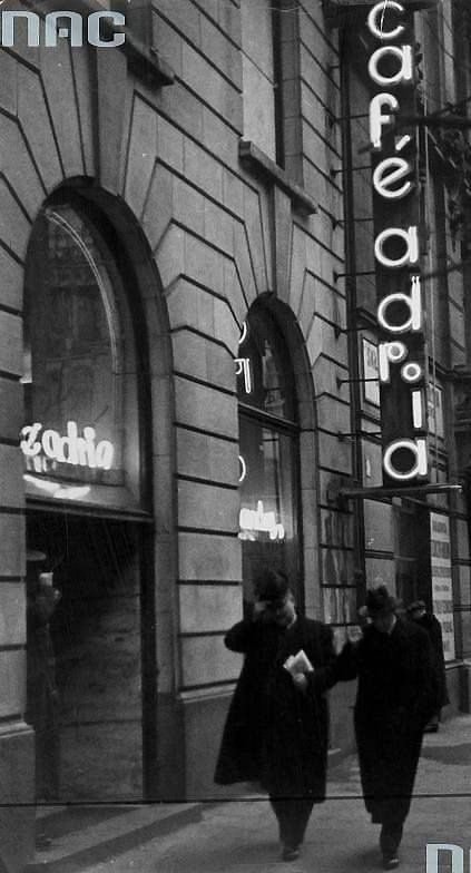 Wejście do Café Adria przy Moniuszki 10 — pionowy neon nad chodnikiem. Fot. Narodowe Archiwum Cyfrowe.