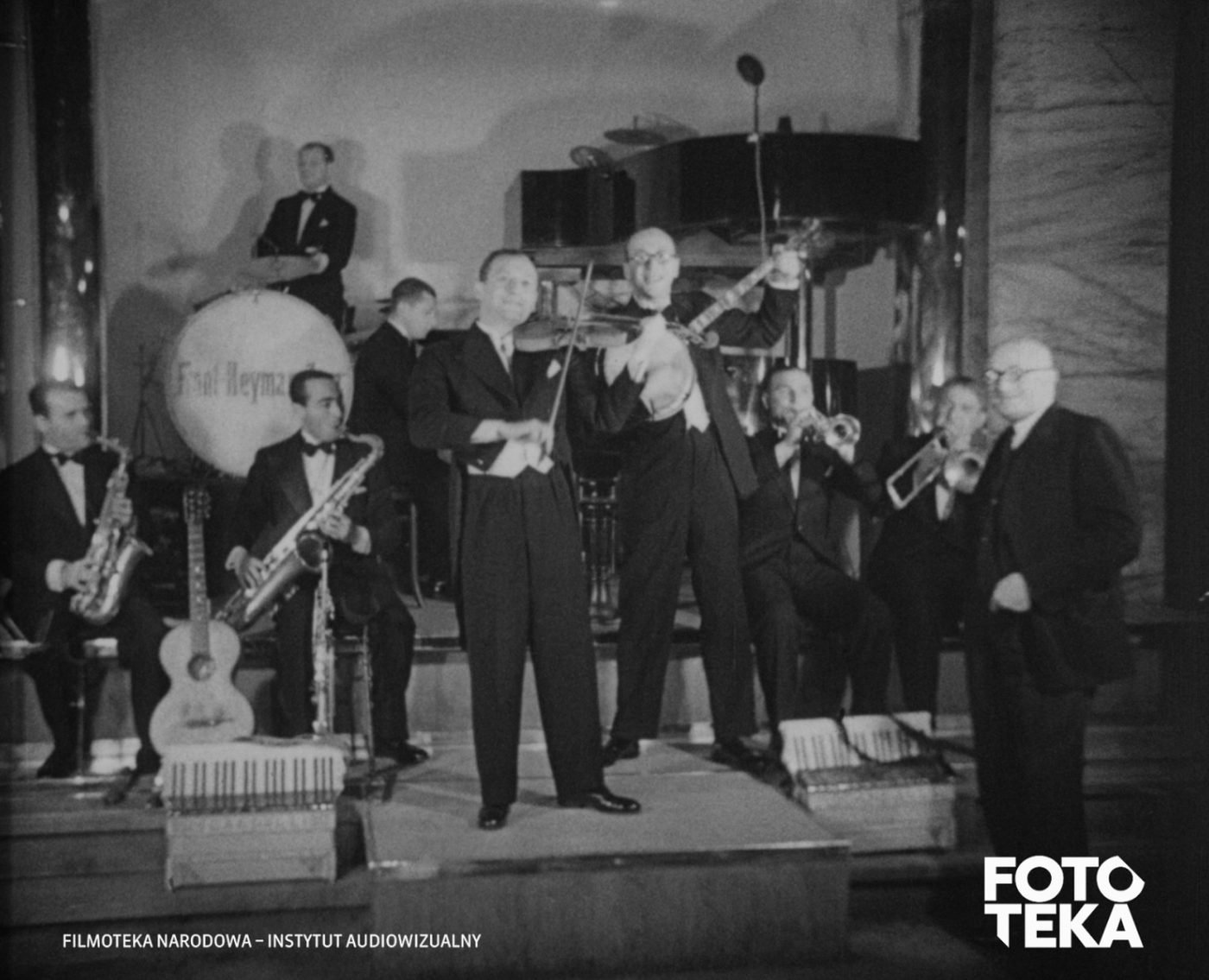 Orkiestra w komplecie na estradzie Adrii, kadr z filmu „Dziś mamy bal”, 1932. Od lewej: Tadeusz Jeselzon (saksofon), Stanisław Ferszko (przy fortepianie), Julian Front (ze skrzypcami), Zygmunt Heyman (z bandżo), Zygmunt Jaroszewski (z puzonem); pierwszy z prawej — Franciszek Moszkowicz, dyrektor Adrii. Na membranie bębna napis „Front Heyman Jazz”. Filmoteka Narodowa — Instytut Audiowizualny, Fototeka.