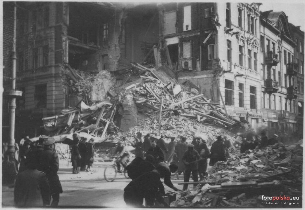 Odgruzowywanie Nowego Światu, jesień 1939: mieszkańcy wybierają
cegły i deski z hałdy przed narożnikiem nr 30; obok przejeżdża
rowerzysta. fotopolska.eu.