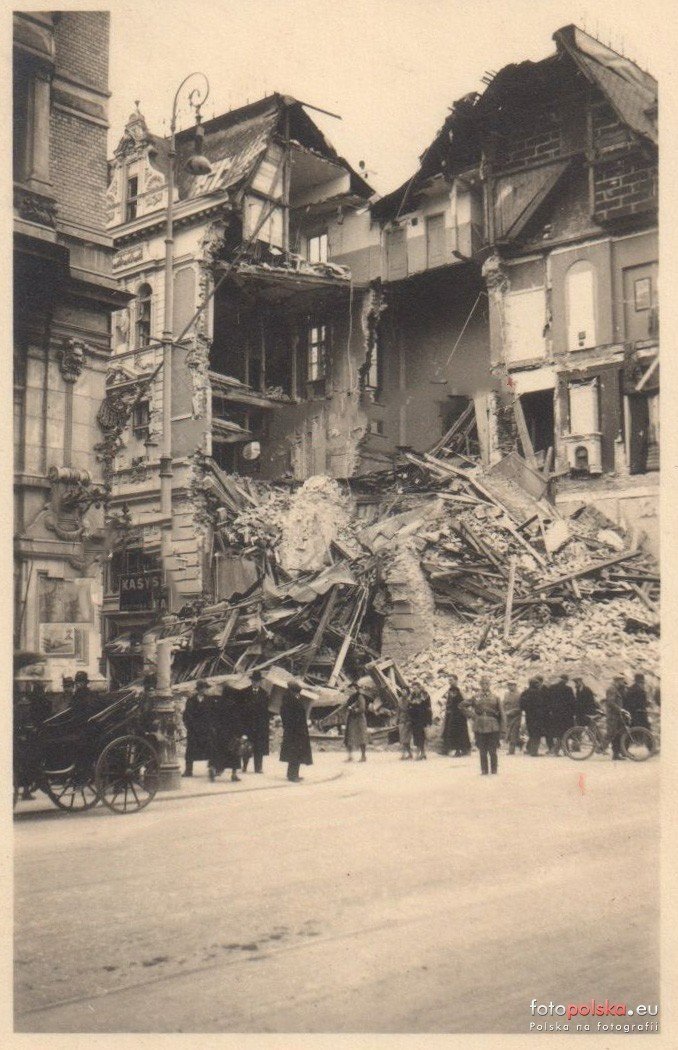 Dorożka pod latarnią, grupa gapiów i pojedynczy niemiecki
żołnierz przed ruiną Nowego Światu 30; na ścianie po lewej tabliczka
„Kasy”. Przełom 1939 i 1940 roku. fotopolska.eu.